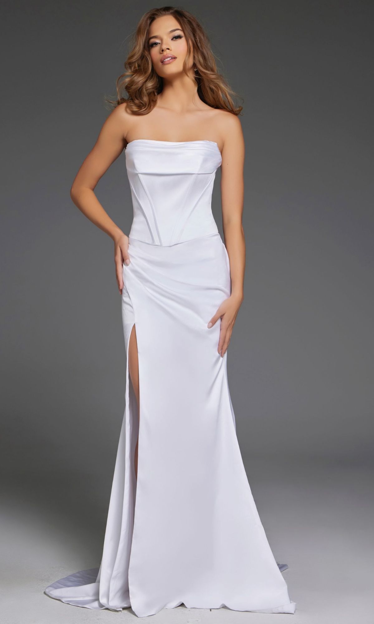 A woman poses against a plain gray background in the Jovani 42355 long prom dress, featuring a strapless satin design with a corset bodice and thigh-high leg slit.